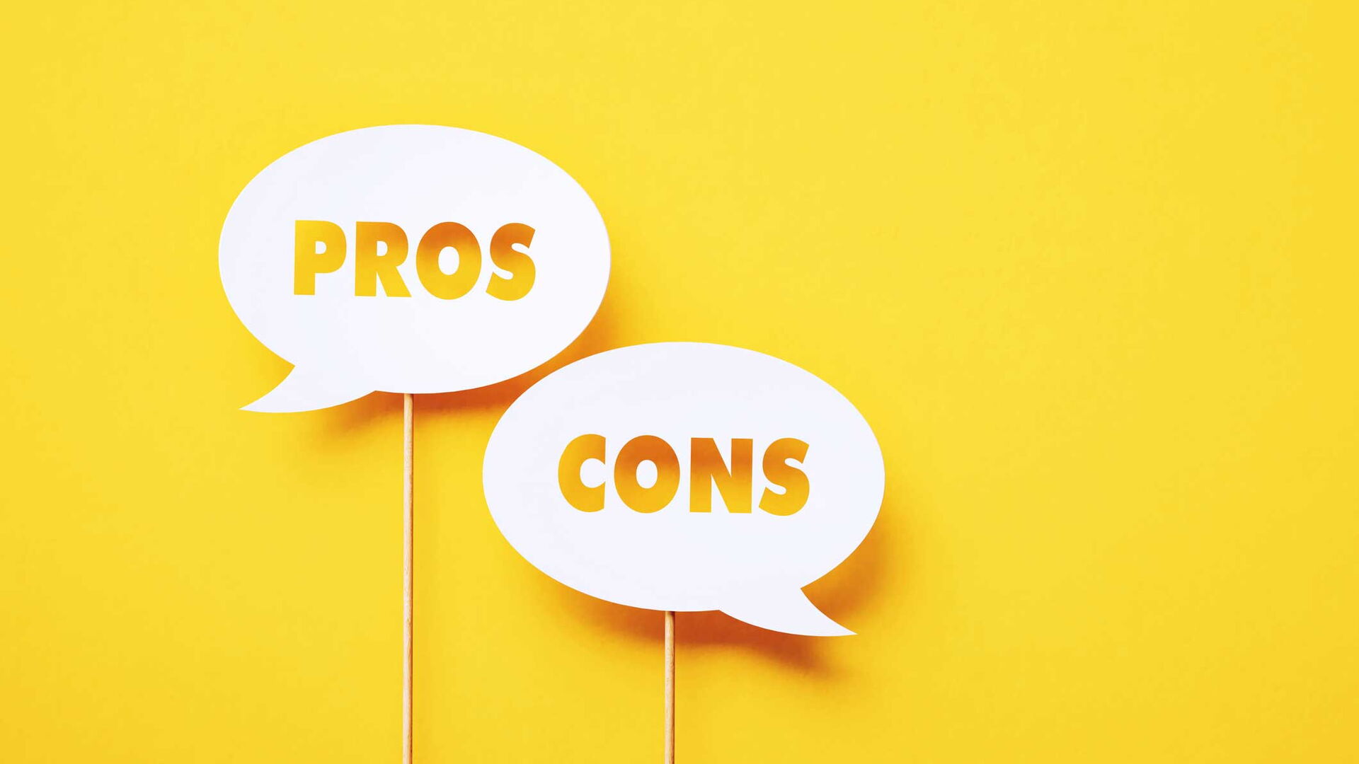 Zwei Sprechblasen-Schilder auf gelbem Hintergrund mit den Worten „Pros“ und „Cons“.