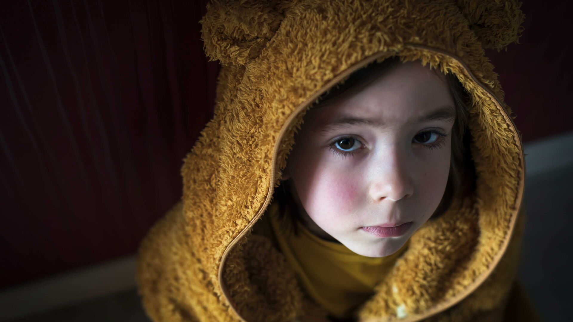 Ein traurig blickendes Kind in einem Teddy-Kostüm